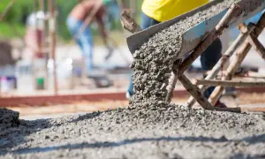 Beton wylewany z rynny na placu budowy. Warto wiedzieć, ile waży kubik betonu, by zaplanować prace.