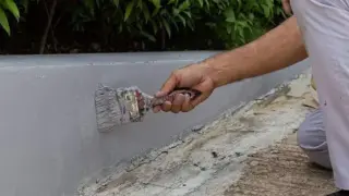 Malowanie betonowego murka na zewnątrz. Szara farba do betonu na zewnątrz zapewnia trwałą ochronę.