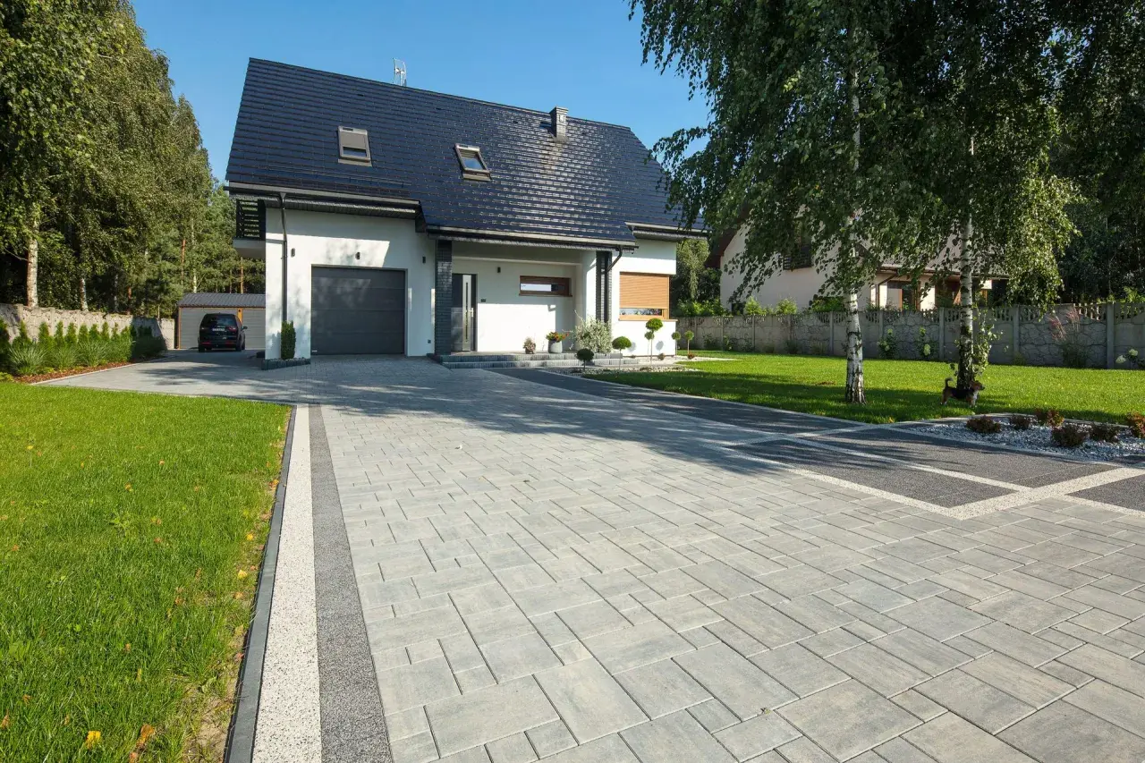 Nowoczesny dom z podjazdem z kostki brukowej. Zastanawiasz się, ile kosztuje ułożenie kostki brukowej?